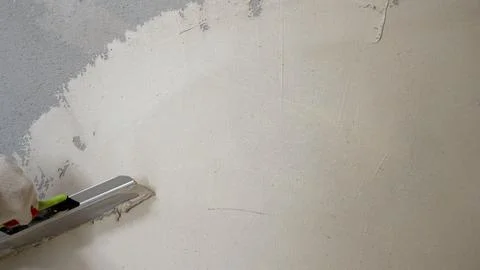 Plaster on a wall. Puttying the wall with beige putty. Stock Photos