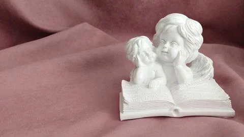 Plaster white statuette of two angels reading a book Stock Photos
