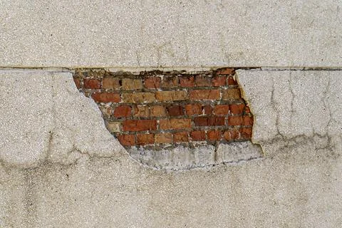 Plastered wall with damage in which bricks are visible Stock Photos