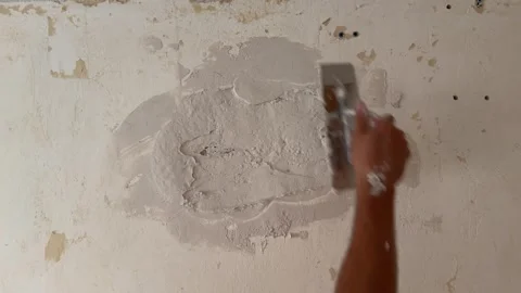 Plasterer applying putty to repair a damaged wall Stockbeeldmateriaal 341362946