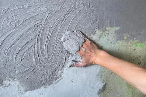 The plasterer Builder puts the plaster on the wall with his hand. Internal co Stock Photos