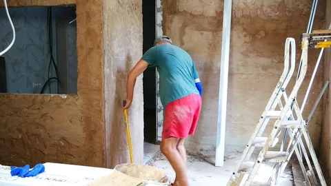 Plasterer cleans the wall from excessive plaster Stock Footage 102900593