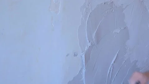Plasterer man is applying plaster on wall to aligning it using trowel, closeup. Video stock 153085458