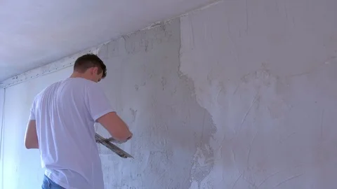 Plasterer man is applying wet plaster on wall to aligning wall using spatula. Stock Footage 123358904