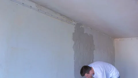 Plasterer man is applying wet plaster on wall to aligning wall using spatula. Stock Footage 152961842