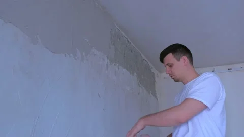 Plasterer man explains how to spackling wall with putty plaster aligning wall. Video stock 137498521