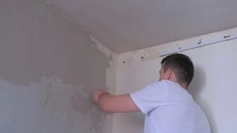 Plasterer man spackling wall with putty plaster aligning wall using trowel. Stock Footage 145003416