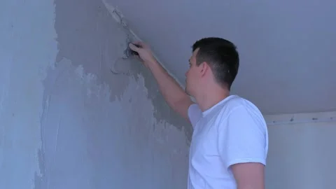 Plasterer man spackling wall with putty plaster aligning wall using trowel. Stock Footage 146164618