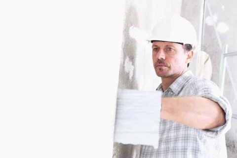 Plasterer man at work with trowel plastering the wall of interior constructio Photos