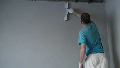 Plasterer Painter Completes Plastering of Wall. Back View. Leveling Raw Plaster Stock Footage 168355631