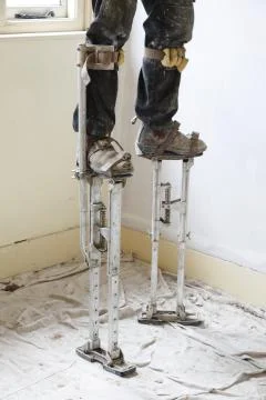 Plasterer plastering on stilts Stock Photos