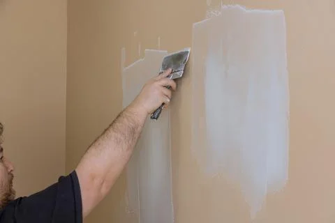 Plasterer plastering wall of drywall at a construction damaged wall repair Stock Photos
