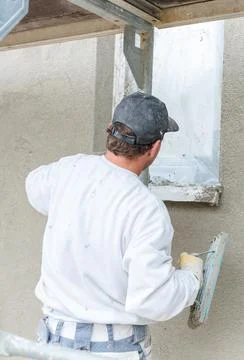 Plasterer smoothing plaster on a facade Stock Photos