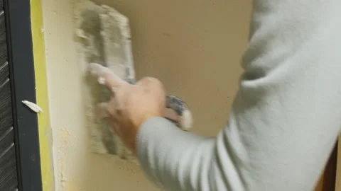 Plasterer smooths out putty layer applied over fiberglass mesh Stock Footage 304419576