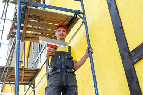 Plasterer with trowel on facade, plastering and smoothing exterior walls, s.. Stock Photos