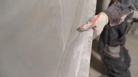 Plasterer using screeder smoothing putty plaster mortar on wall. Smoothing out Stock Photos