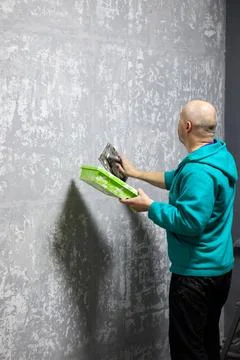 Plasterer at work on the wall, using a trowel to apply decorative plaster for Stock Photos