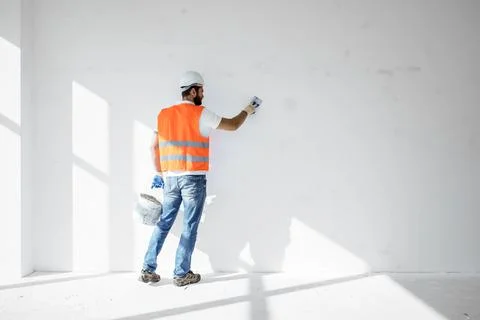 Plasterer in workwear smoothing wall surface of building indoors Fotos de archivo