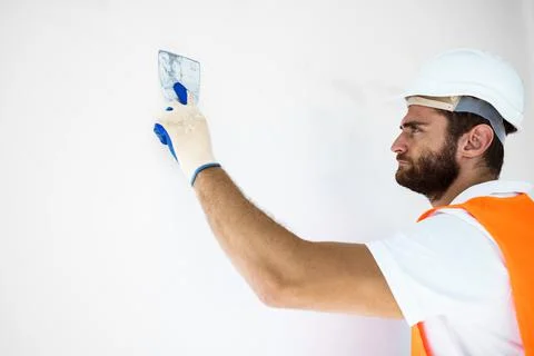 Plasterer in workwear smoothing wall surface of building indoors Fotos de archivo