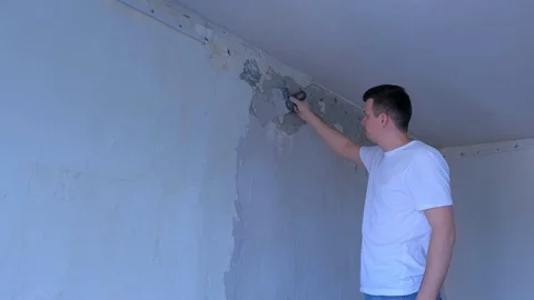 Plasterer young man is spackling wall with putty plaster aligning the wall. Stock Footage 123348512