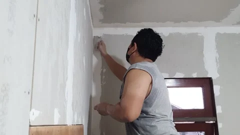 Plasterwork and wall painting preparation. Asian male applying plaster or f.. Stock Footage 259136134