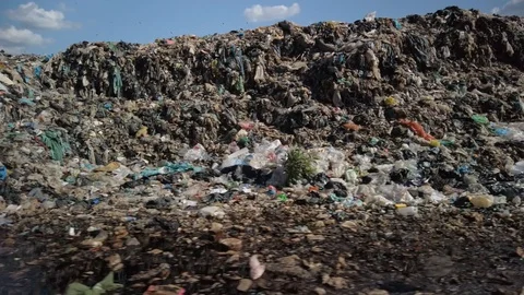 Plastic and garbage in piles that look like a small city set against a blue sky. Stock Footage 128813280