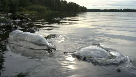 Plastic bag and bottle floating in the water of the lake near the shore. Close Stock Footage 139397960