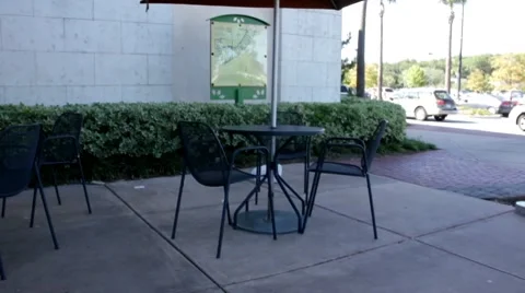 Plastic bag blowing in the wind by a sidewalk coffee shop table Stock Footage 8765242