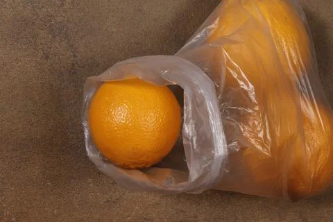 A plastic bag, like a container, is filled with oranges. Foto stock