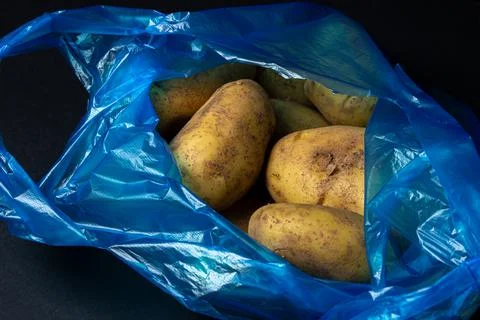 Plastic bag with potatoes on a black background. Stock Photos