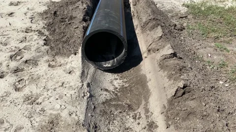 Plastic black pipe lies on the sand ground Stock Footage 203788568
