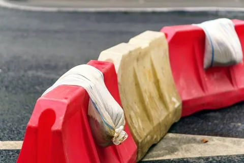 Plastic blocks for restricting traffic are reinforced with sandbags Stock Photos