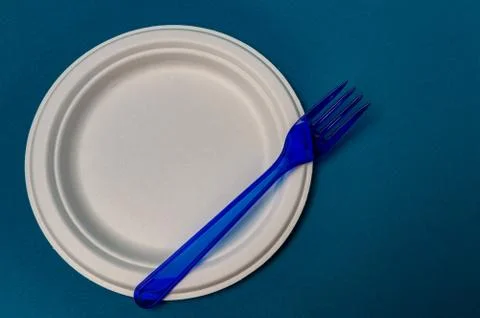 Plastic blue fork, plastic plate on a blue background. closeup Stock Photos