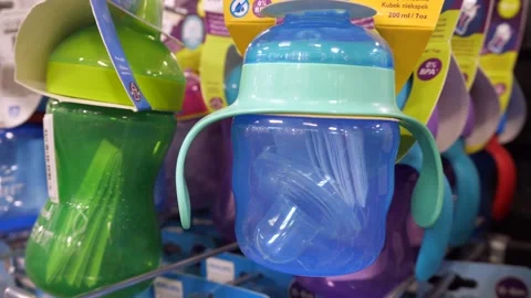 Plastic blue sippy cup and other baby sippy cups hanging on a shelf in a store. Stock Footage 306168092