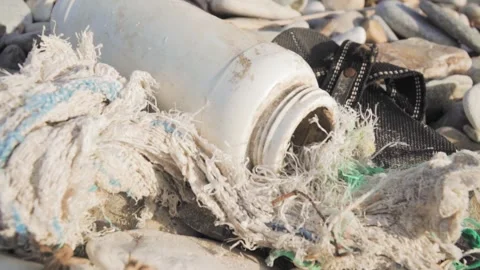 Plastic bottle and old shoe polluting beach Stock Footage 289663369