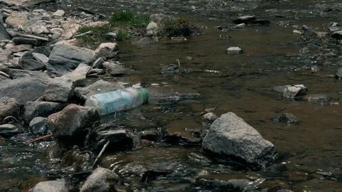 Plastic bottle and pollution in mountain river washes up onto stones Stock Footage 90347902