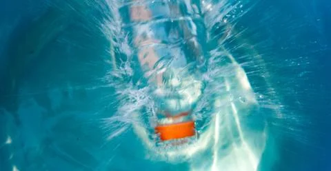 Plastic bottle falling into the water making splashes and spraying drops Foto stock