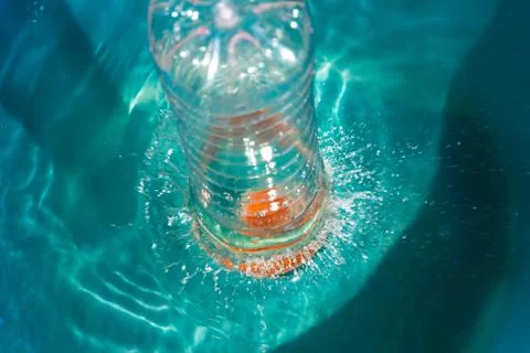 Plastic bottle falling into the water making splashes and spraying drops Stock Photos