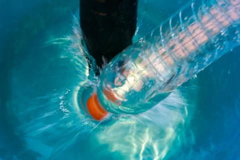 Plastic bottle falling into the water making splashes and spraying drops Foto stock