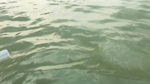 Plastic bottle float in Buriganga river water pollution tilting up to boats on Stock Footage 346453162