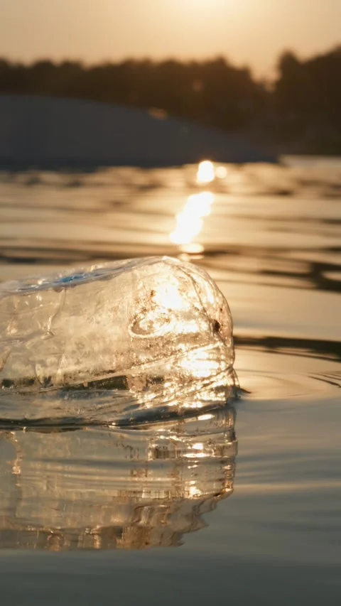 Plastic Bottle Floating in Calm Lake Water During Golden Hour Sunset Video stock 343574047