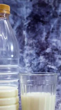 A plastic bottle of fresh regular milk and a glass beaker on a dark gray marb Stock Photos