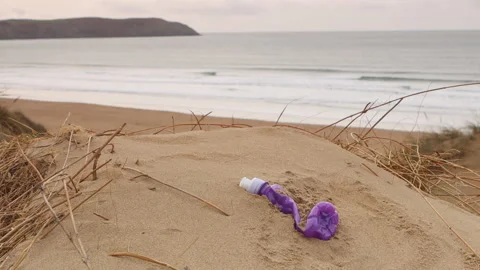 Plastic bottle half buried on Woolacombe beach in Devon, UK Stock Footage 170306964