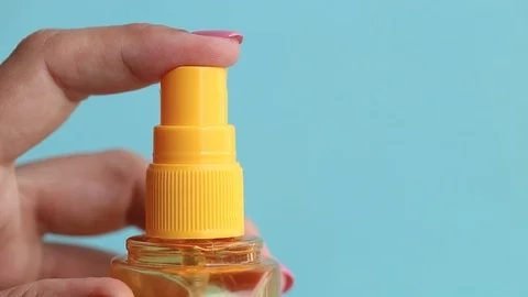 Plastic bottle isolated on blue background. Woman pressing top of it to spray 库存影片 104106648