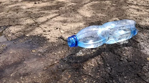 Plastic bottle leaking water on dry ground outdoors environmental pollution Stock Footage 335137414
