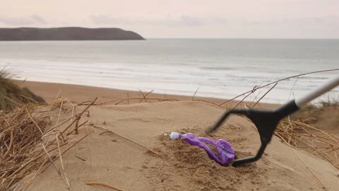 Plastic bottle litter being picked up on Woolacombe beach in Devon, UK Stock Footage 170304013