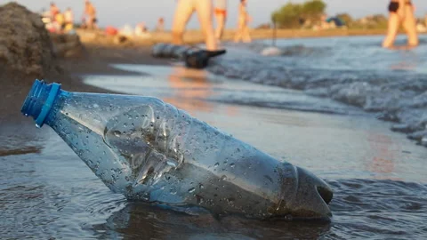 A plastic bottle is lying on the beach. Waves wash over it. Close-up, slow Video stock 124330608