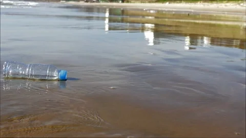 Plastic bottle lying on a sandy beach in the water Video stock 136950811