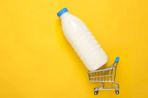 Plastic bottle with milk inside in a small shopping cart Stock Photos