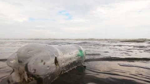 Plastic bottle with a plastic straw thrown as trash in the waves Stock Footage 302204727